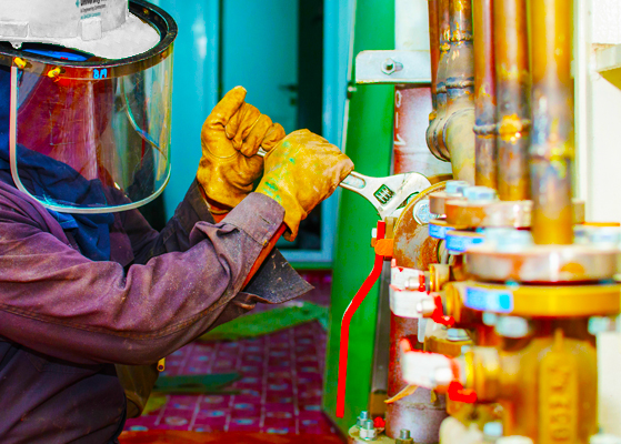 Worker in safety gear working on tightening pipies with a wrench